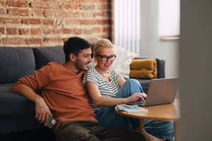 Two people smiling using laptop